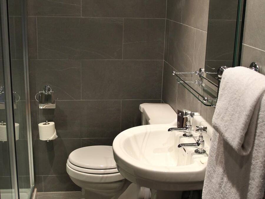 Un baño moderno con inodoro, lavamanos y cabina de ducha de vidrio.