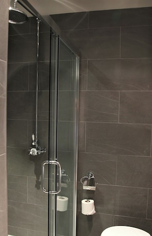 A shower with a glass door, a toilet paper holder, and a towel rack. - The Penny Farthing (Berkhamsted)