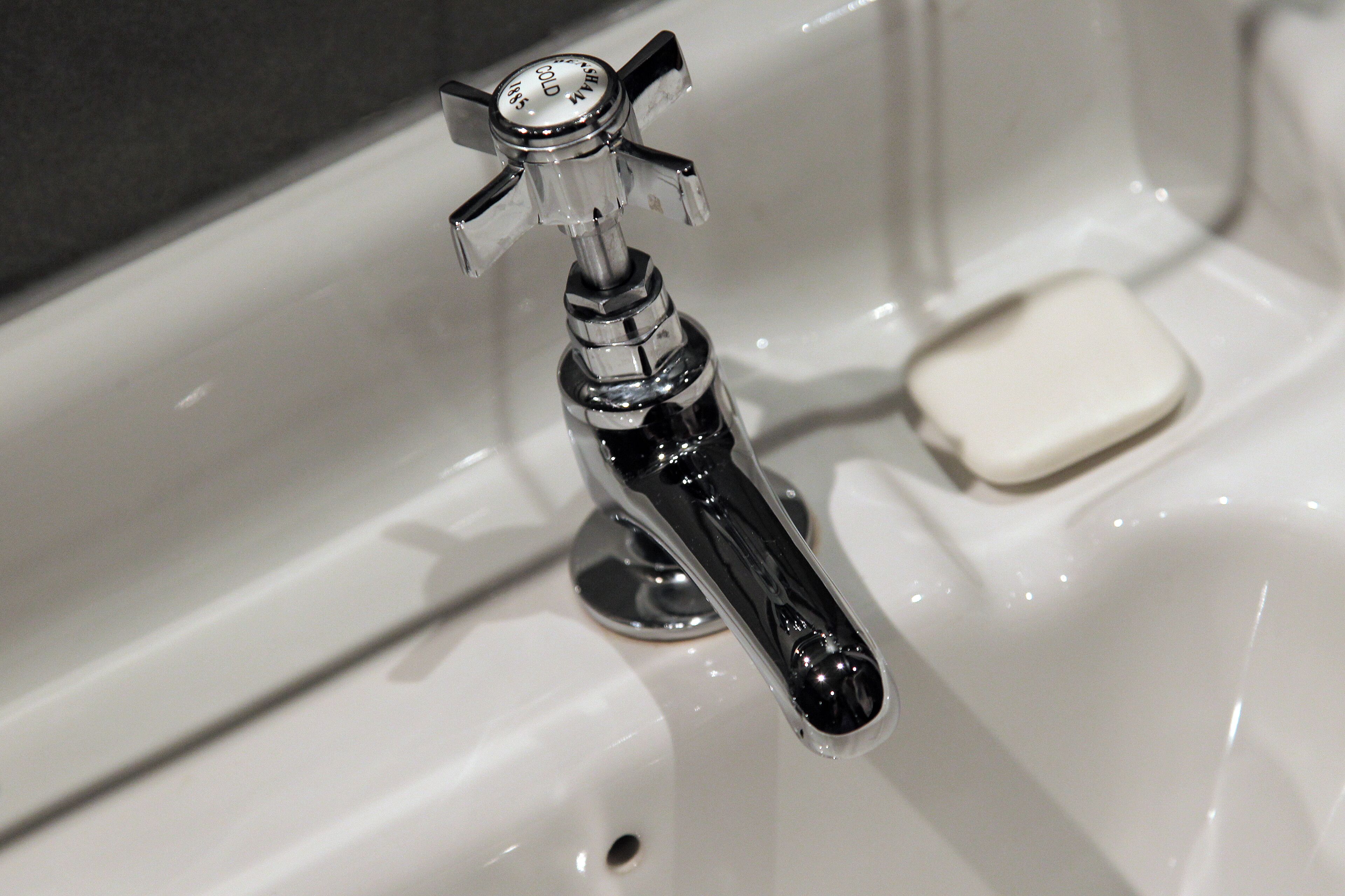 A bathroom sink with a chrome faucet, a soap dish, and a mirror.