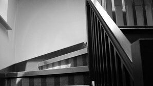 A staircase with a wooden handrail and a light fixture above it. - The Penny Farthing (Berkhamsted)