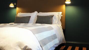 A neatly made bed with a striped bedspread and two pillows, a headboard, and two wall-mounted lamps.