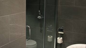A modern bathroom with a glass-enclosed shower, a white toilet, and a sink.