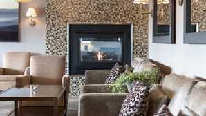 A cozy living room with a fireplace, comfortable seating, and decorative wall tiles. - Tyrifjord Hotell (Modum)