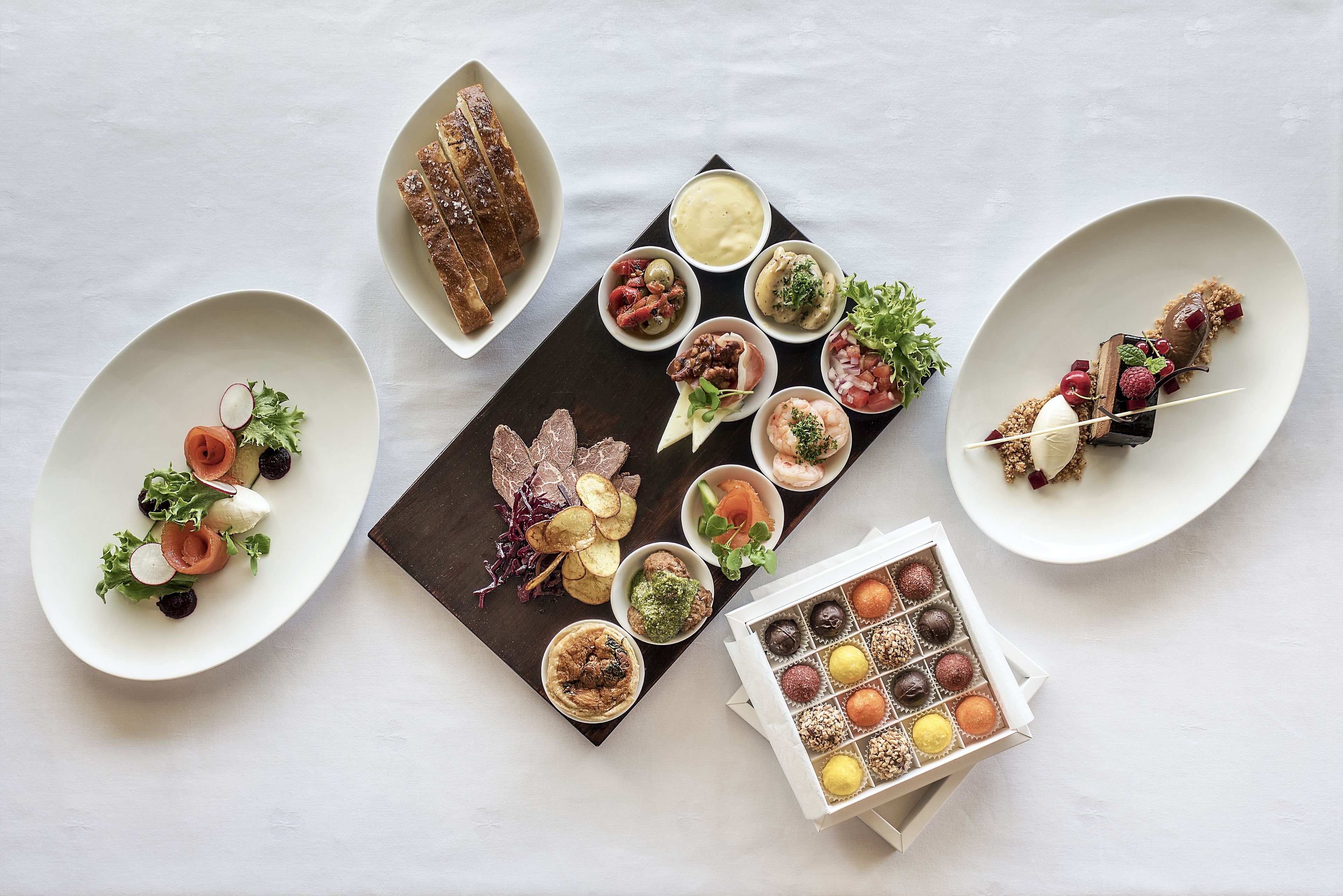 A variety of appetizers and desserts on a white table.