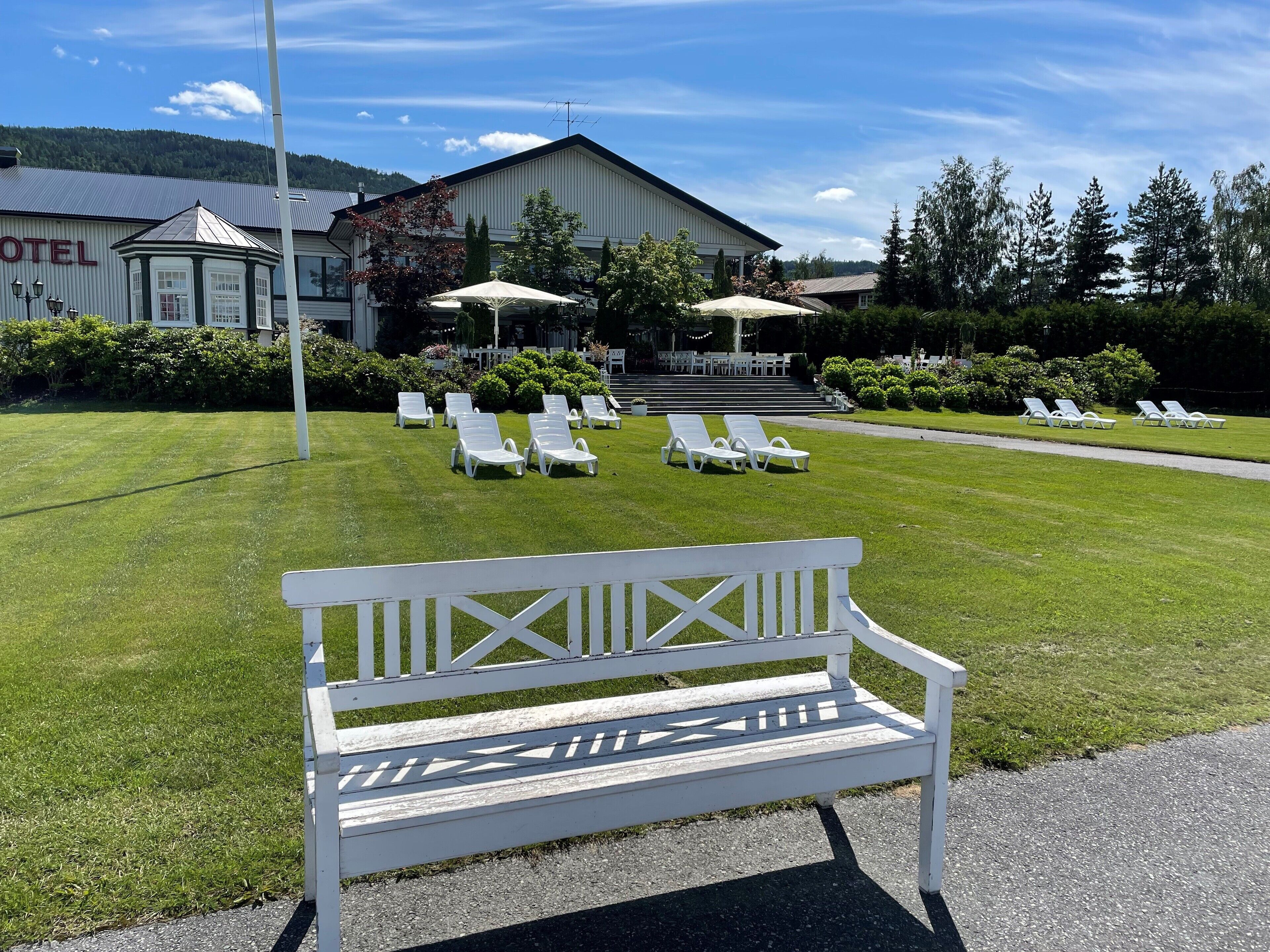 A hotel with a well-maintained lawn, outdoor seating area, and a prominent building with a sign.