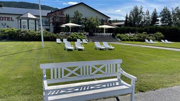A hotel with a well-maintained lawn, outdoor seating area, and a prominent building with a sign.