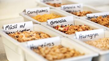 Différents types d’aliments sont présentés dans des contenants étiquetés, notamment des céréales, des flocons de maïs et du muesli.