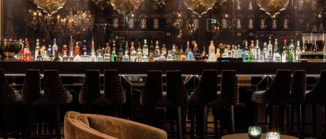 A bar area with multiple hanging light fixtures, a variety of liquor bottles, and bar stools.