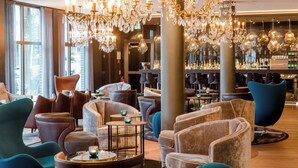 Un área de estar moderna con asientos cómodos, candelabros y un bar con diversas botellas.