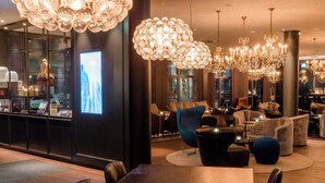 Un vestíbulo de hotel moderno con una amplia recepción, zonas de estar cómodas y elegantes candelabros.