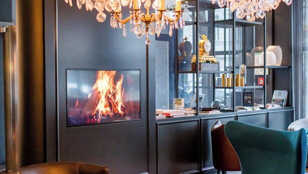 Una sala de estar moderna con una gran lámpara de araña, chimenea y muebles contemporáneos.