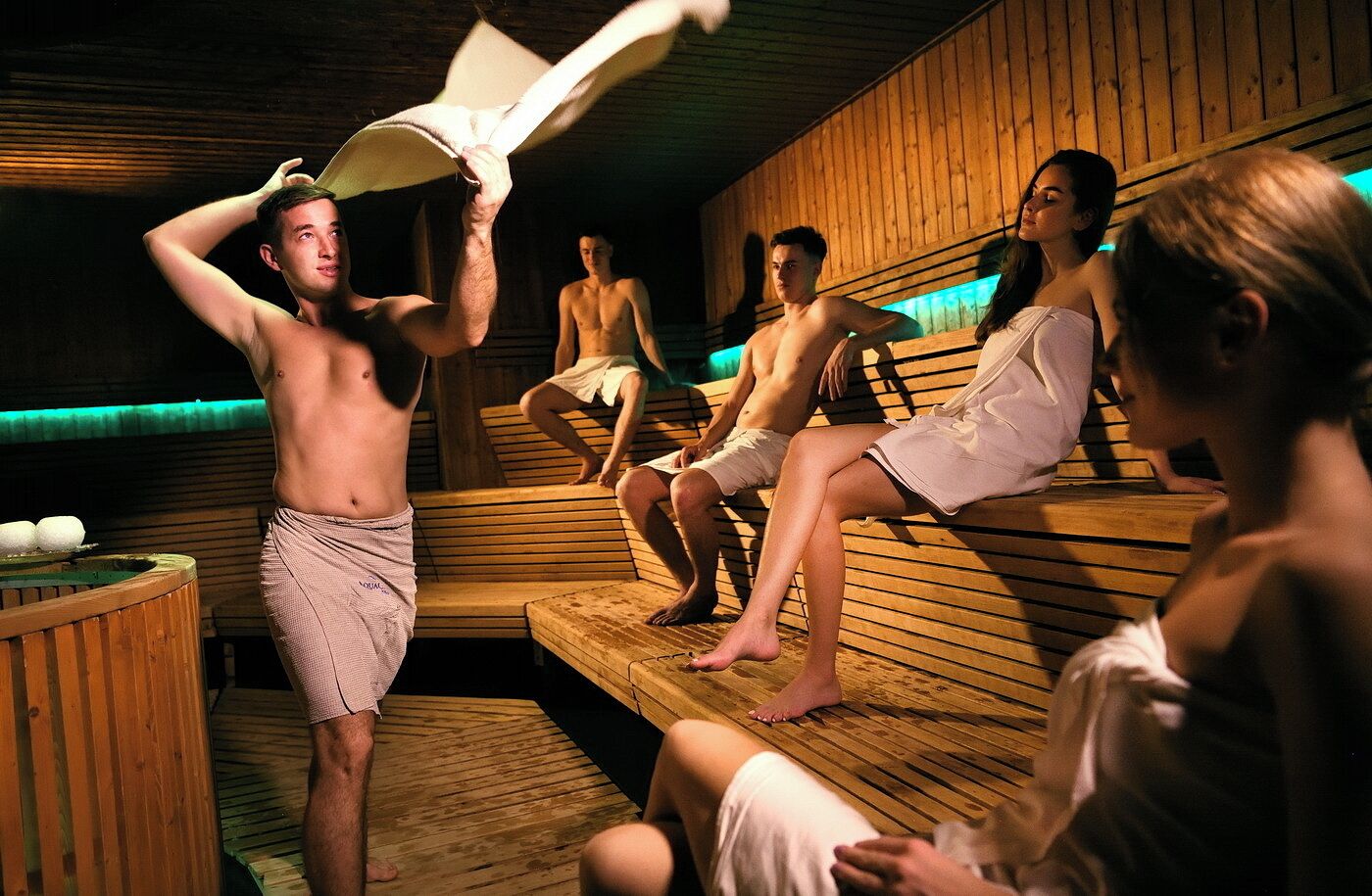 Una sauna con bancos de madera y una persona sosteniendo una toalla.