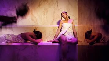 A spa setting with marble walls and a person sitting on a bench.