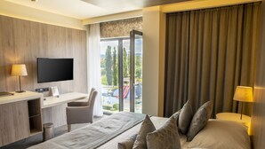 Une chambre d’hôtel avec un lit, un bureau avec une télévision, une chaise et une vue sur l’extérieur.