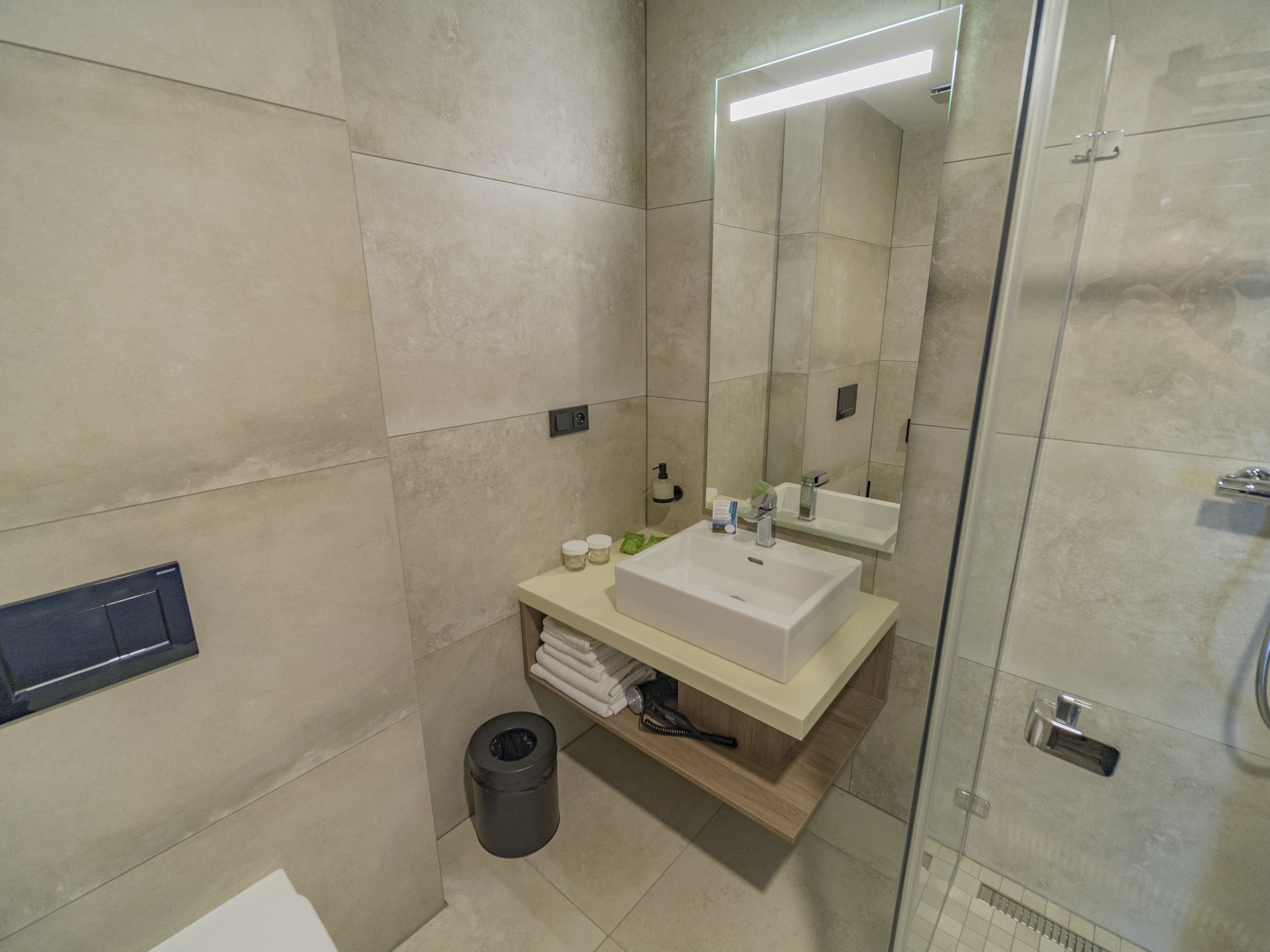 Un baño moderno con un espejo grande, un lavabo y una zona de ducha.