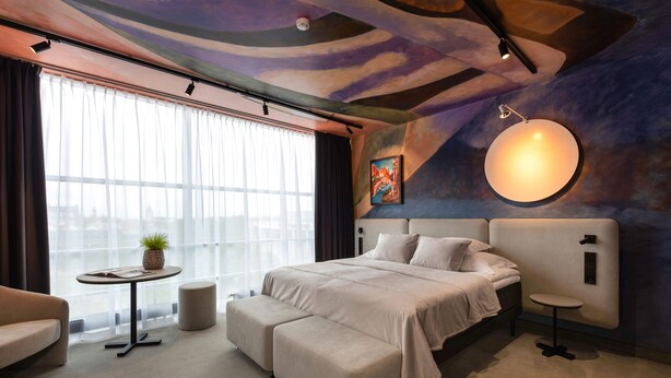 A modern hotel room with a large bed, a small round table, a sofa, and a large window with curtains. - Art hotel Pallas by Tartuhotels (Tartu)