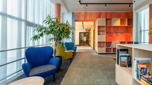 A modern library with colorful chairs, a large bookshelf, and a view through large windows. - Art hotel Pallas by Tartuhotels (Tartu)