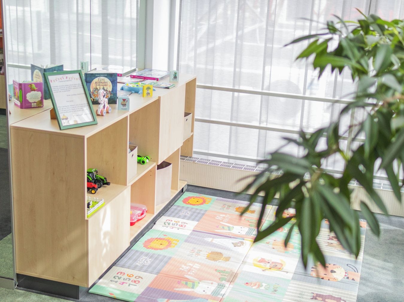 Zona de juegos para niños con una estantería de madera, juguetes y un tapete de colores.