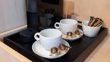 Espai de cafè amb cafetera, tasses i càpsules de cafè sobre un safata.