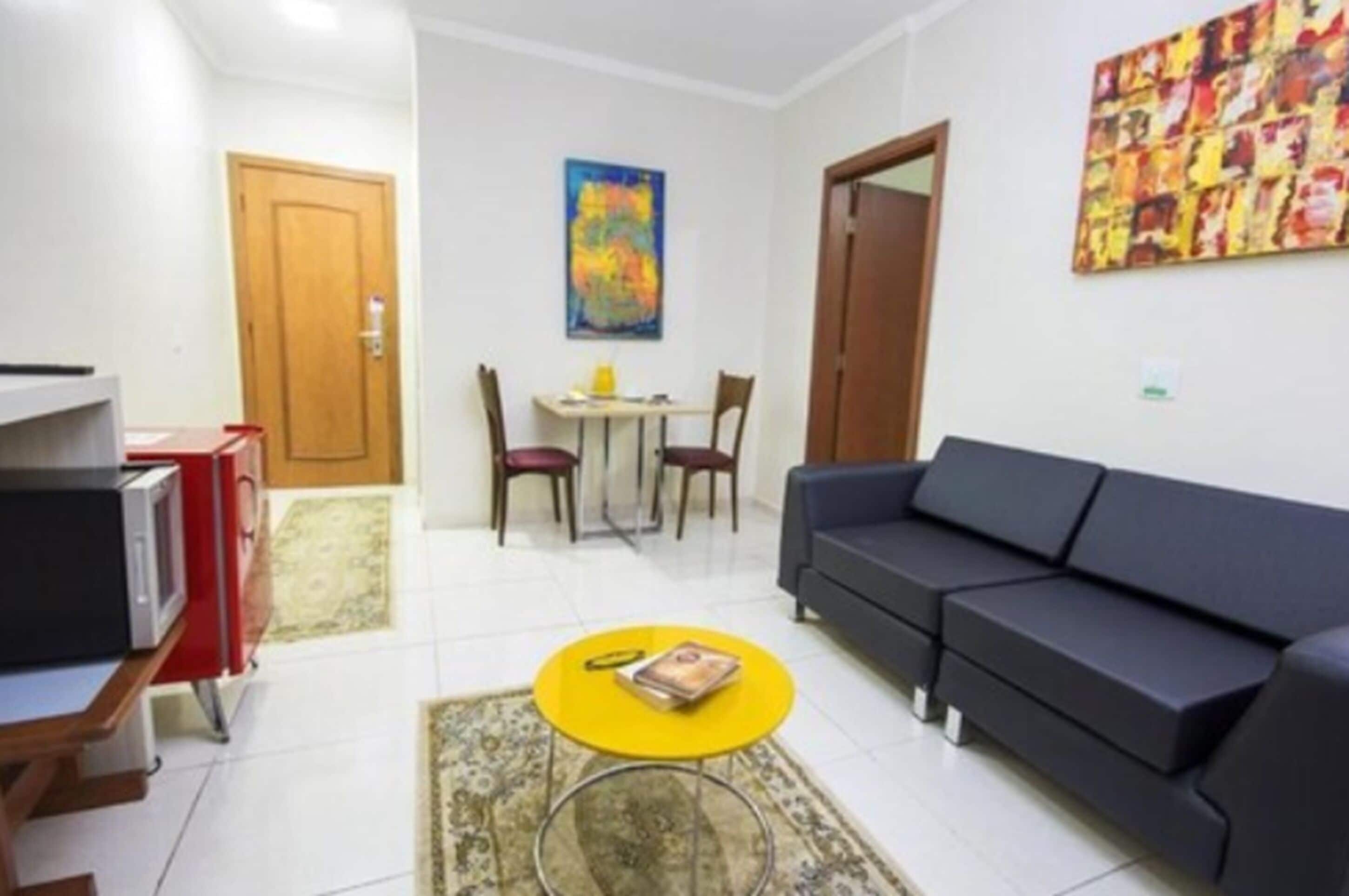 A living room with a sofa, a coffee table, a TV, and a painting on the wall.