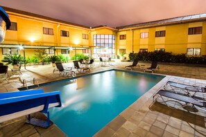 An indoor swimming pool with lounge chairs and tables, surrounded by yellow walls and potted plants. - Hotel Nacional Inn Sorocaba (Sorocaba)