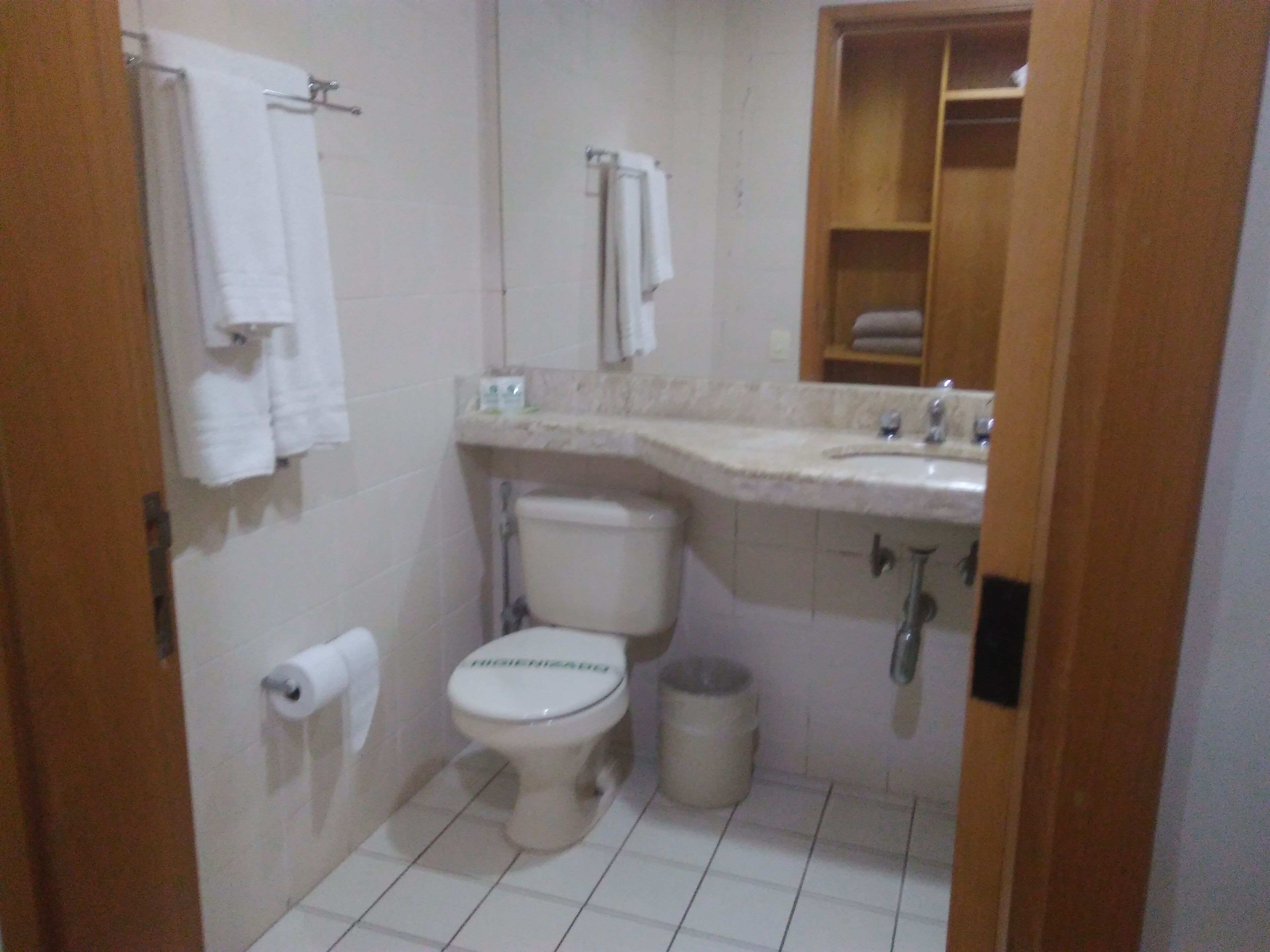 A small bathroom with a toilet, sink, and a towel rack.