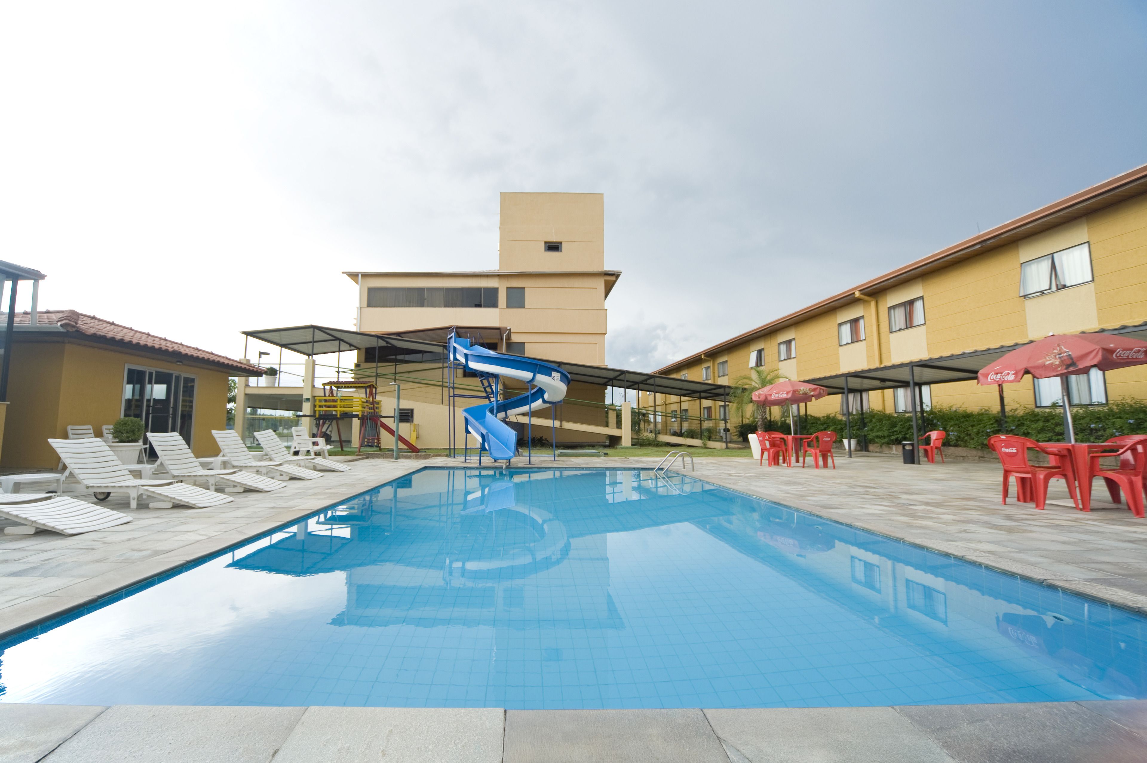Ein Swimmingpool mit Liegestühlen und einer Rutsche, umgeben von Gebäuden mit Außenbereich.