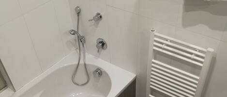 A modern bathroom with a bathtub, a sink, and a towel rack.