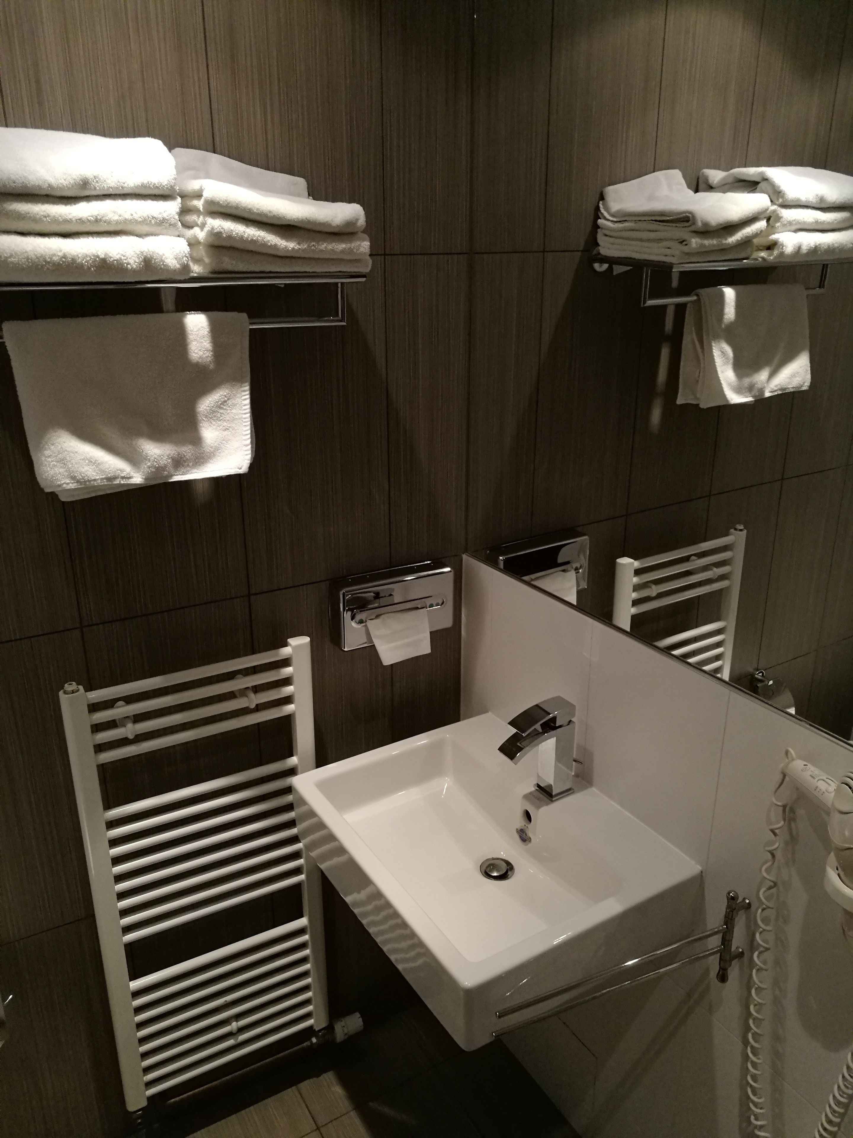 Une salle de bain moderne avec un lavabo blanc, des porte-serviettes et un miroir.