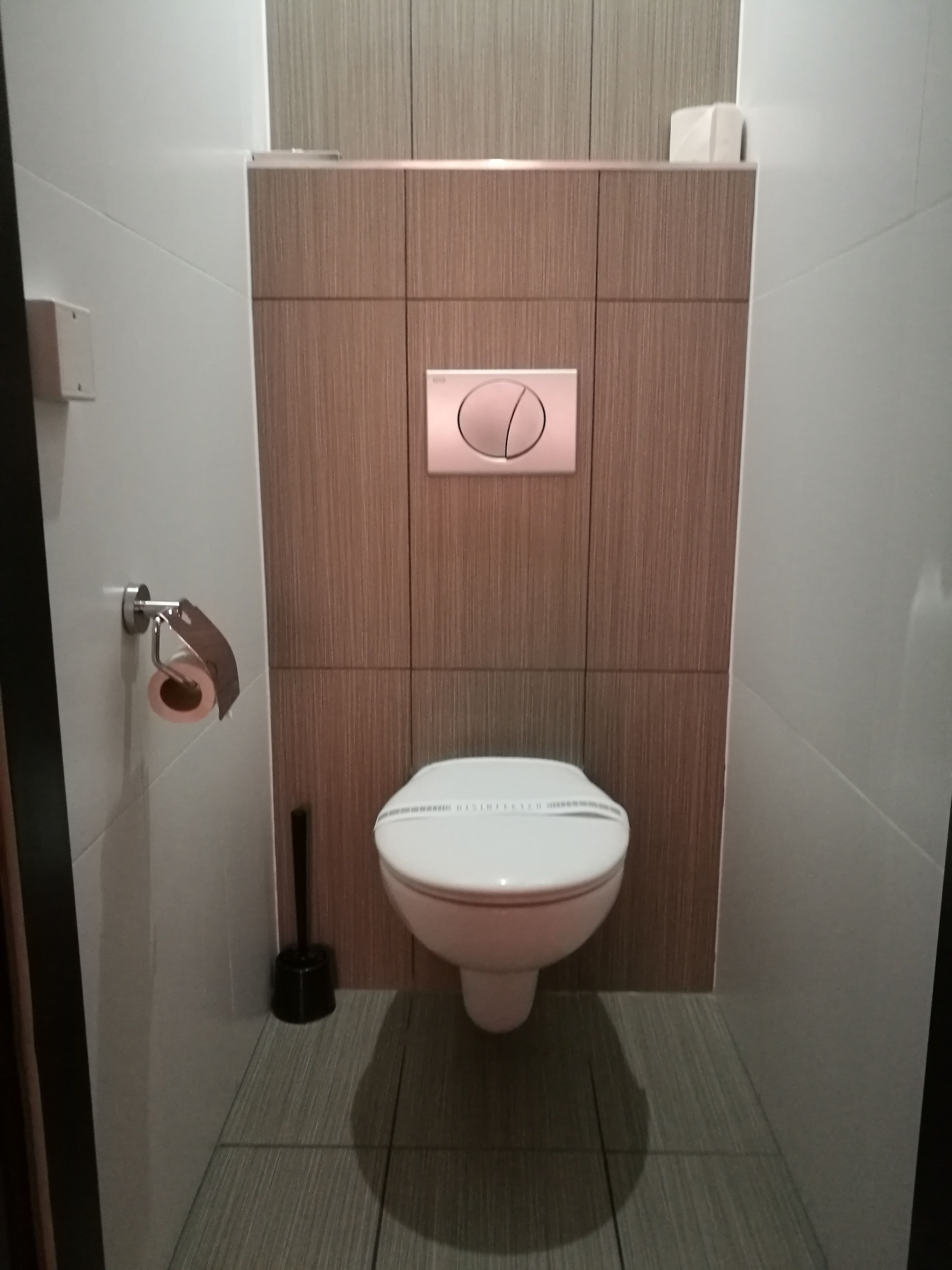 A modern bathroom with a toilet, a bidet, and a toilet paper holder.