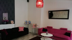 Sala de estar com dois sofás, uma mesa de centro, um tapete, TV na parede e uma mesinha com objetos.