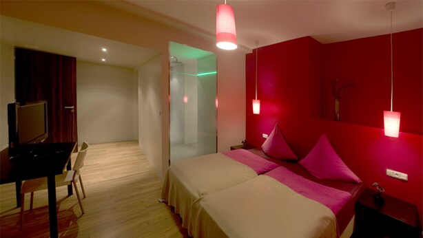 Quarto de hotel com duas camas, uma escrivaninha e uma televisão.