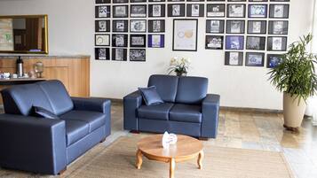 A room with two blue sofas, a wooden coffee table, and a wall decorated with framed pictures.