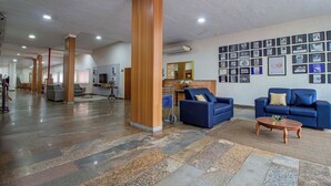 A spacious lobby with a marble floor, wooden pillars, blue sofas, and a reception desk. - Hotel Dan Inn Barretos By Nacional Inn  (Barretos)