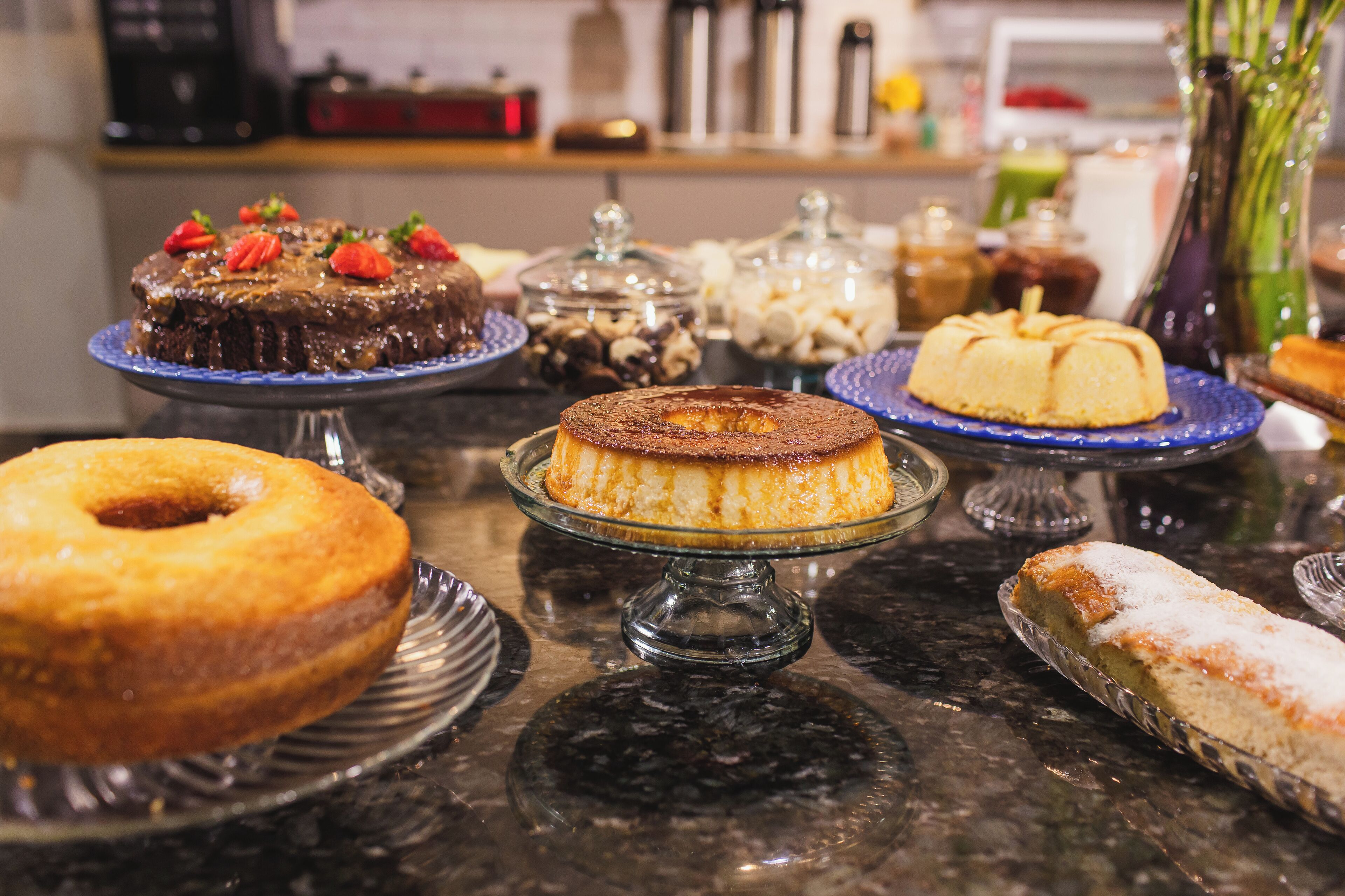 A variety of desserts on display, including cakes and pastries, on a marble countertop.