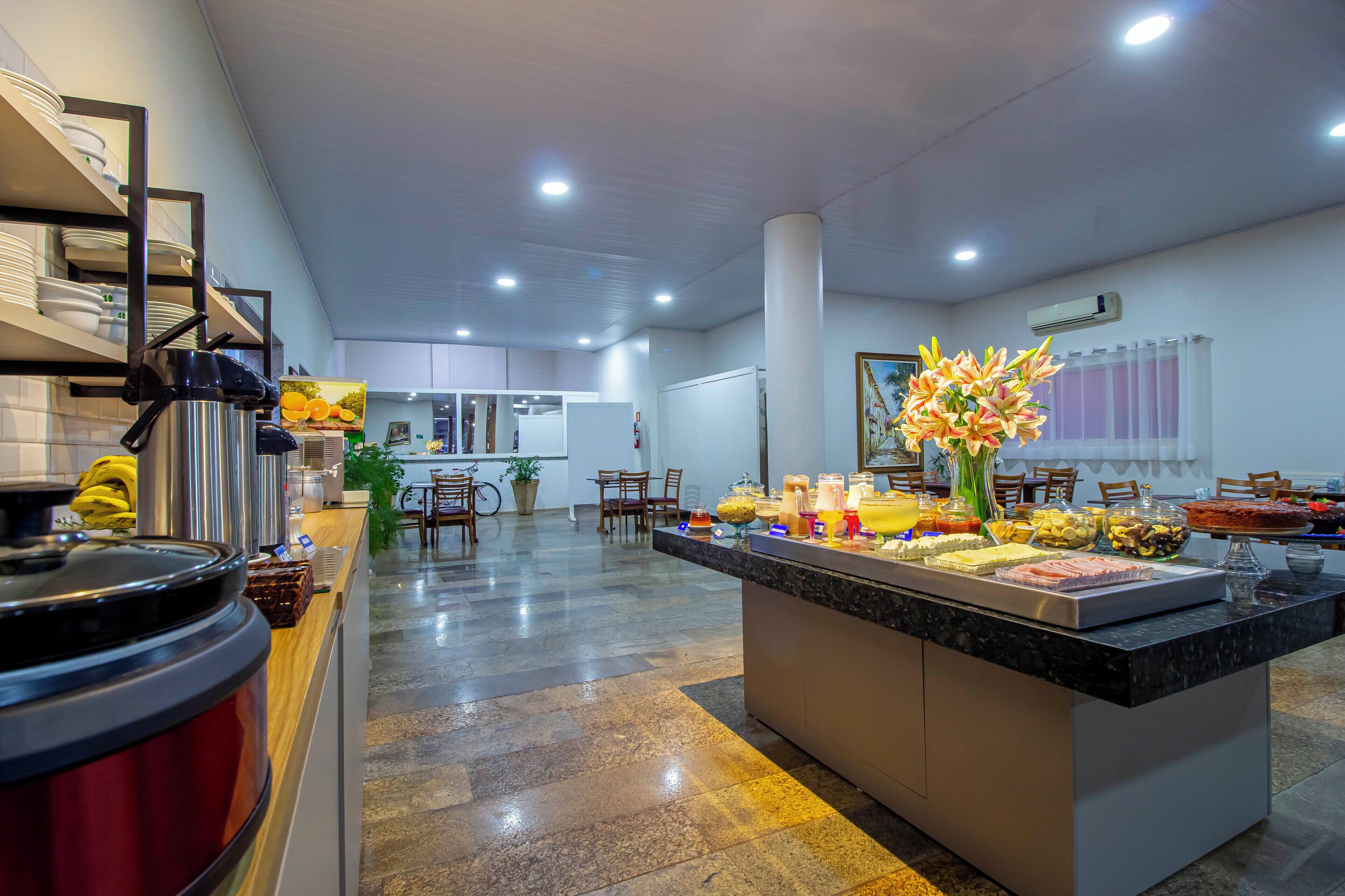 Un moderno vestíbulo de hotel con una zona de buffet, un mostrador de recepción y un área de descanso.