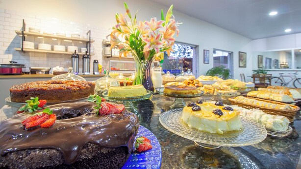 A buffet table with various desserts and a vase of flowers. - Hotel Dan Inn Barretos By Nacional Inn  (Barretos)
