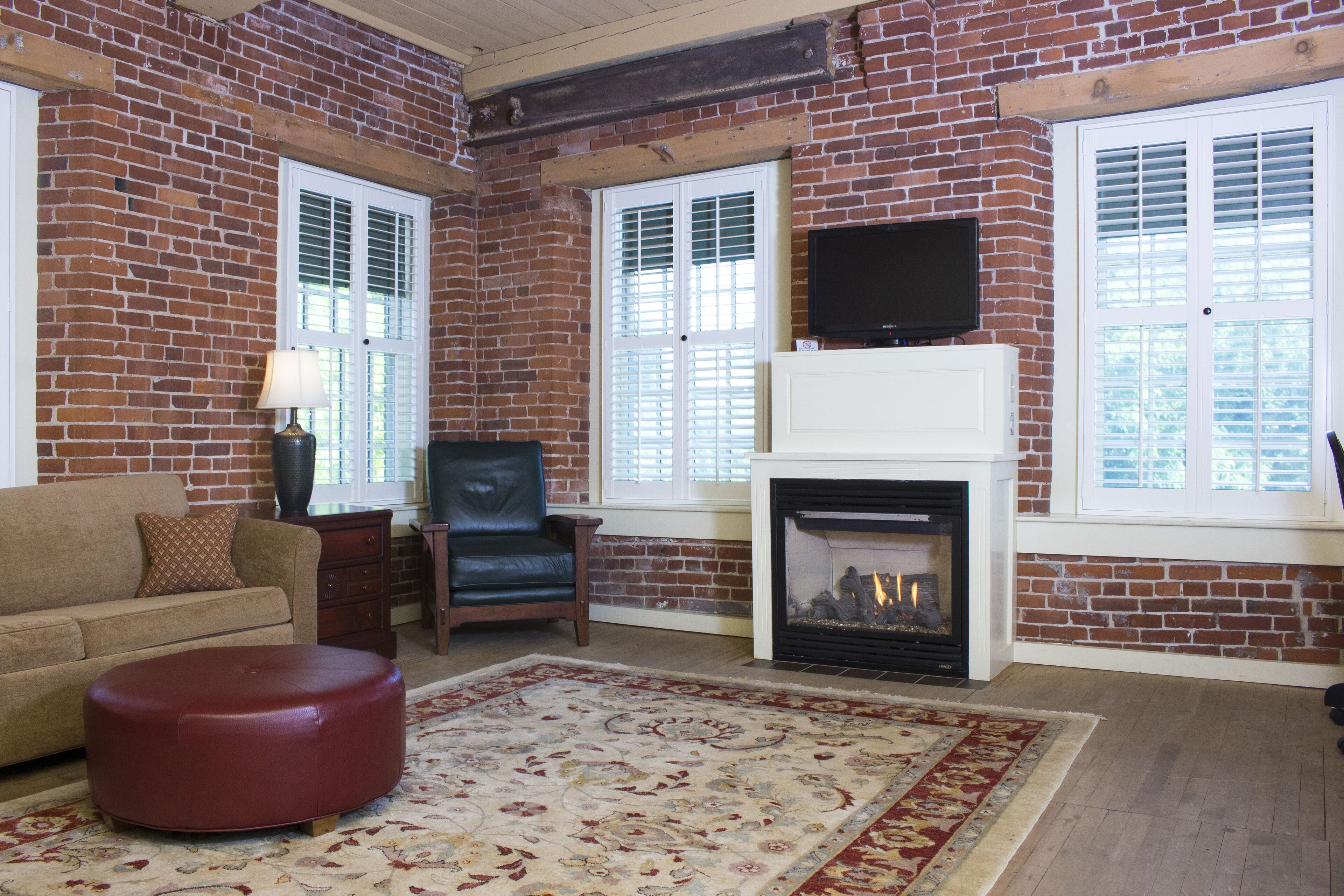 A living room with a brick wall, a fireplace, a television, and a sofa.