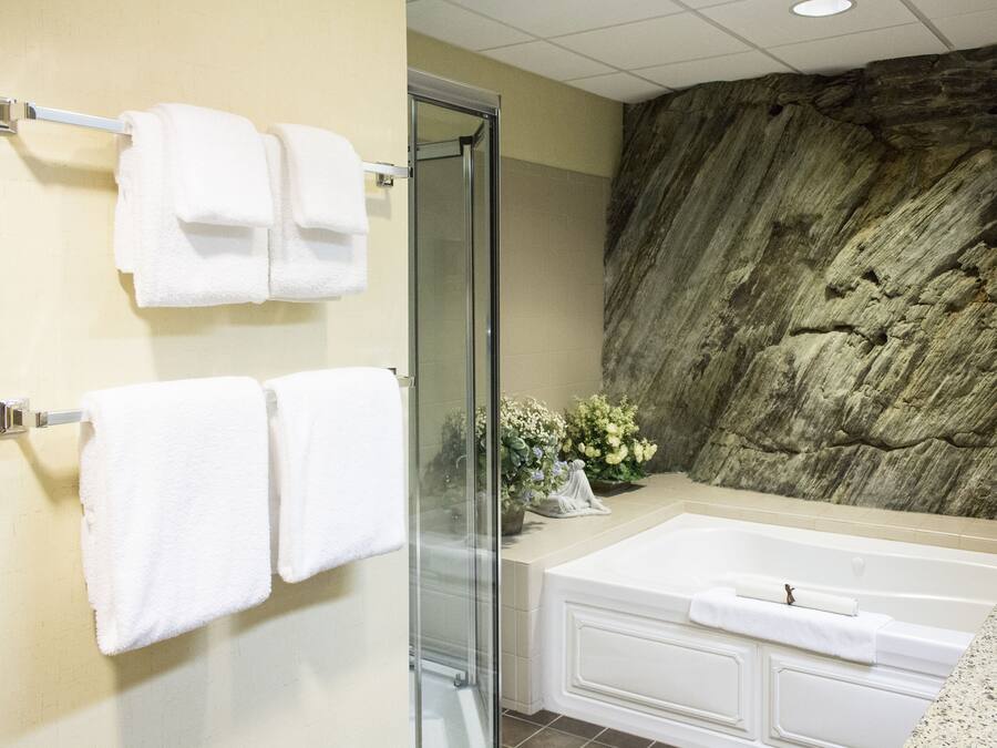 A bathroom with a bathtub, a glass shower enclosure, and towels hanging on a rack.