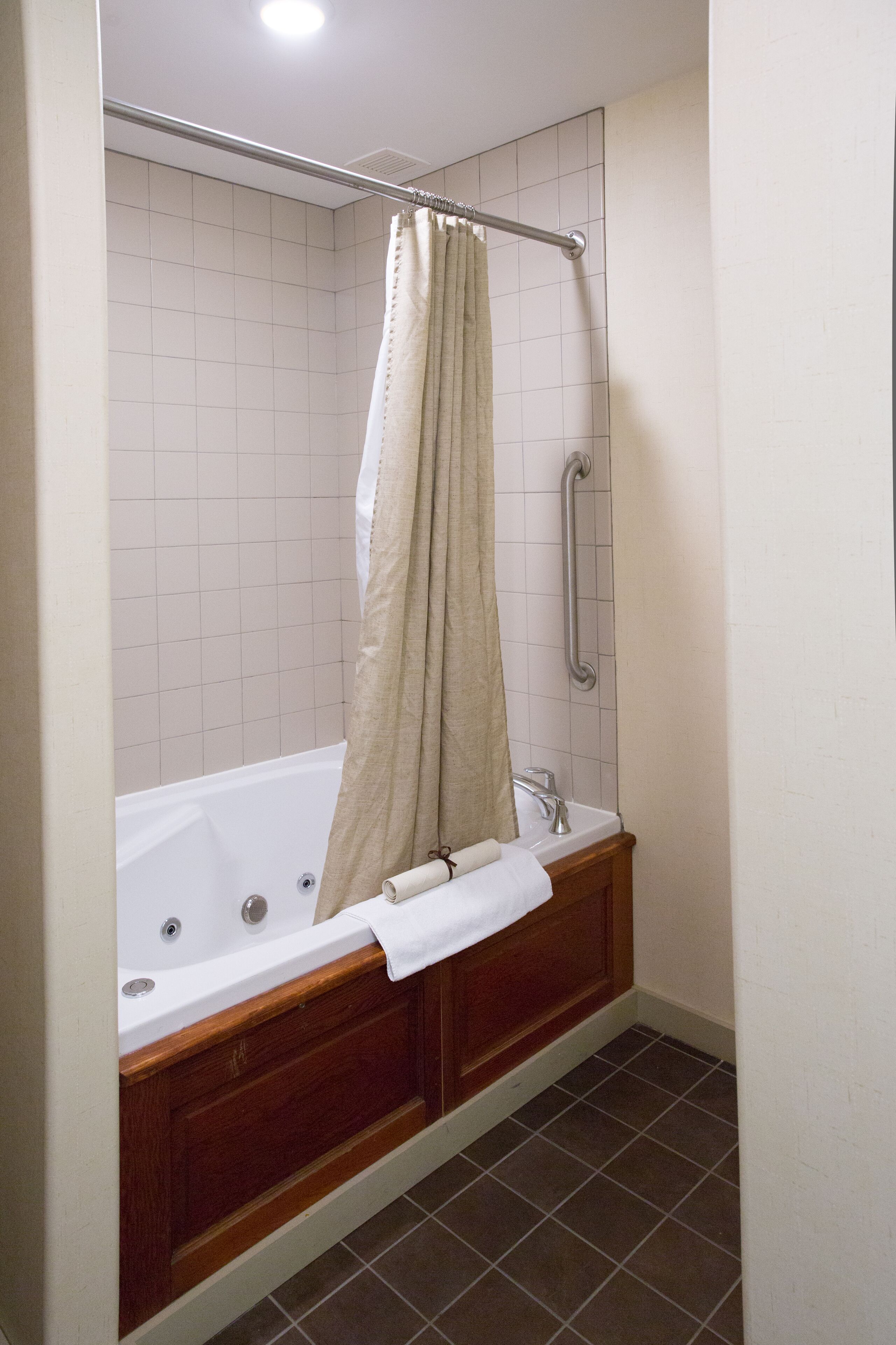A bathroom with a bathtub, a shower with a grab bar, and a wooden vanity.