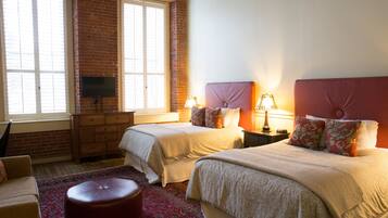 A bedroom with two beds, a television, a dresser, and a red carpet.