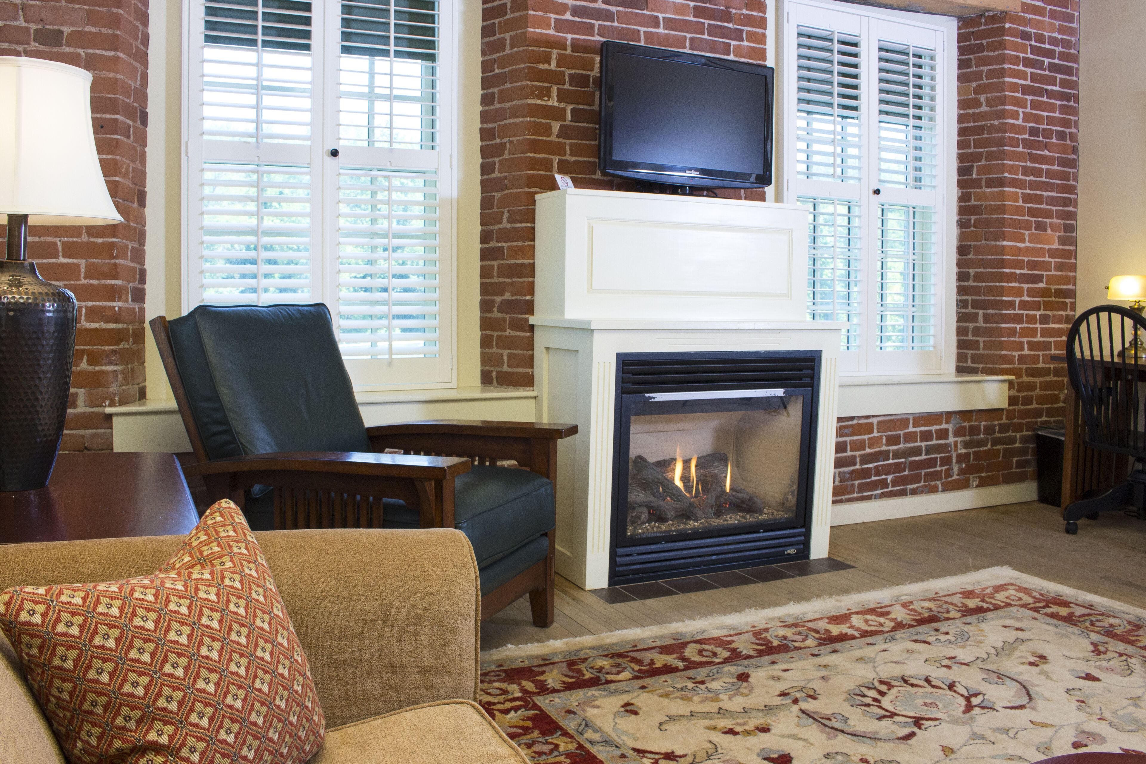 A living room with a fireplace, a television mounted above it, and a patterned rug on the floor.