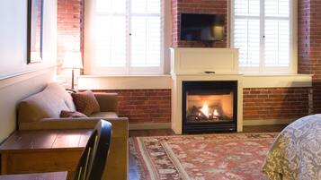 A cozy room with a fireplace, wooden furniture, and large windows.