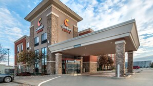 Un hôtel Comfort Suites avec une façade en briques, de grandes fenêtres et une entrée abritée.