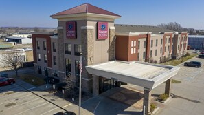 A Comfort Suites hotel with a covered parking area, multiple buildings, and a clear sky.
