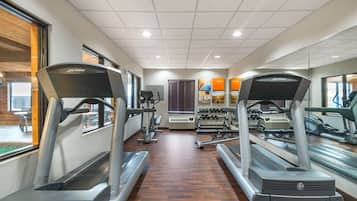 A gym with treadmills, weight machines, and a mirrored wall.