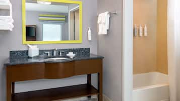 Un baño con lavamanos de encimera de granito, un espejo con marco amarillo, un perchero y una zona de ducha.