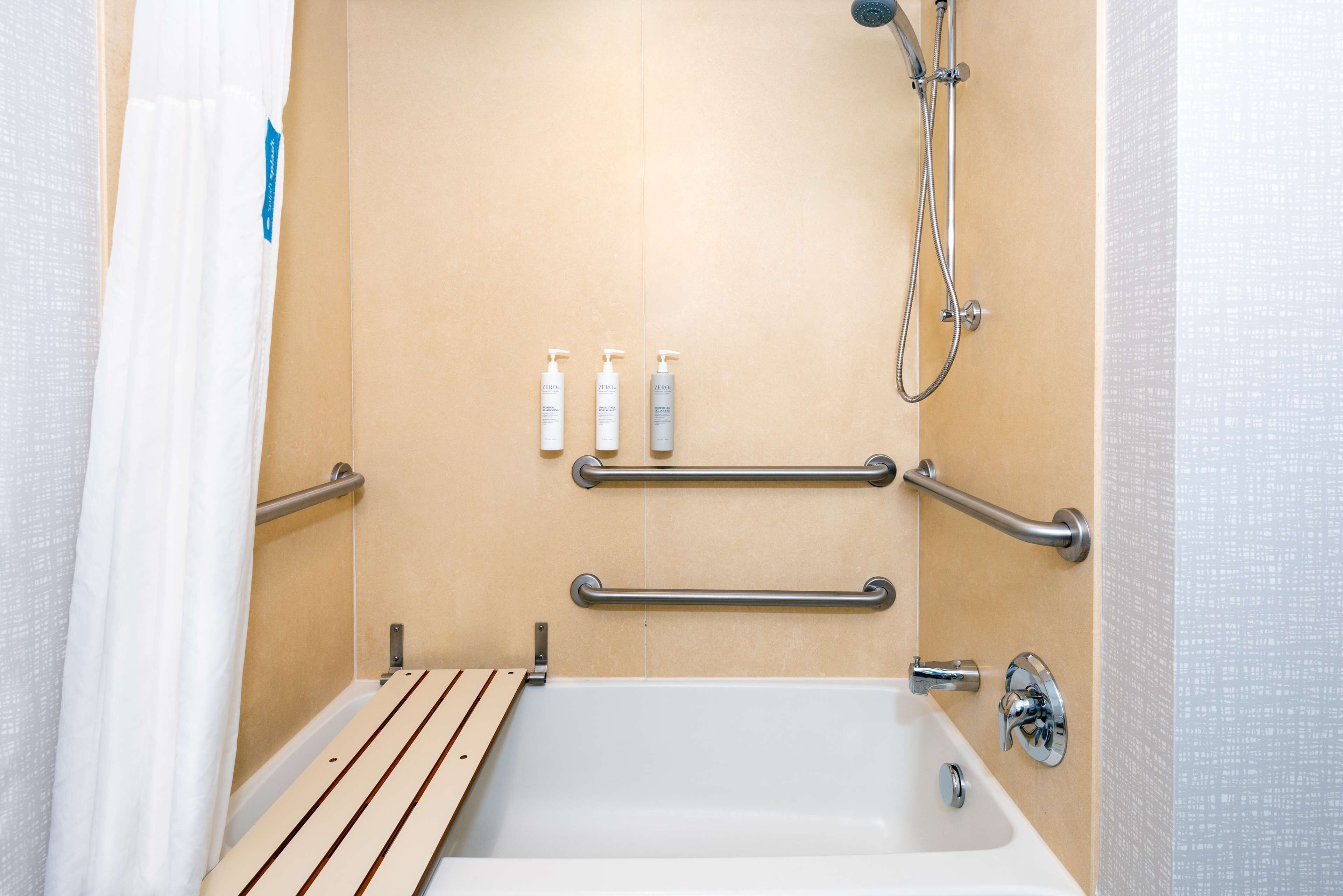 Une salle de bain équipée d’une baignoire, de barres d’appui et d’un pommeau de douche.
