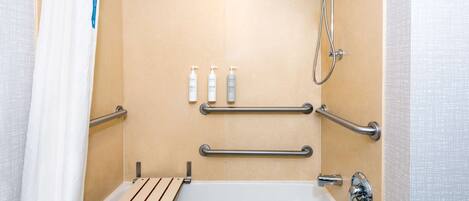 A bathroom with a bathtub, grab bars, and a showerhead.