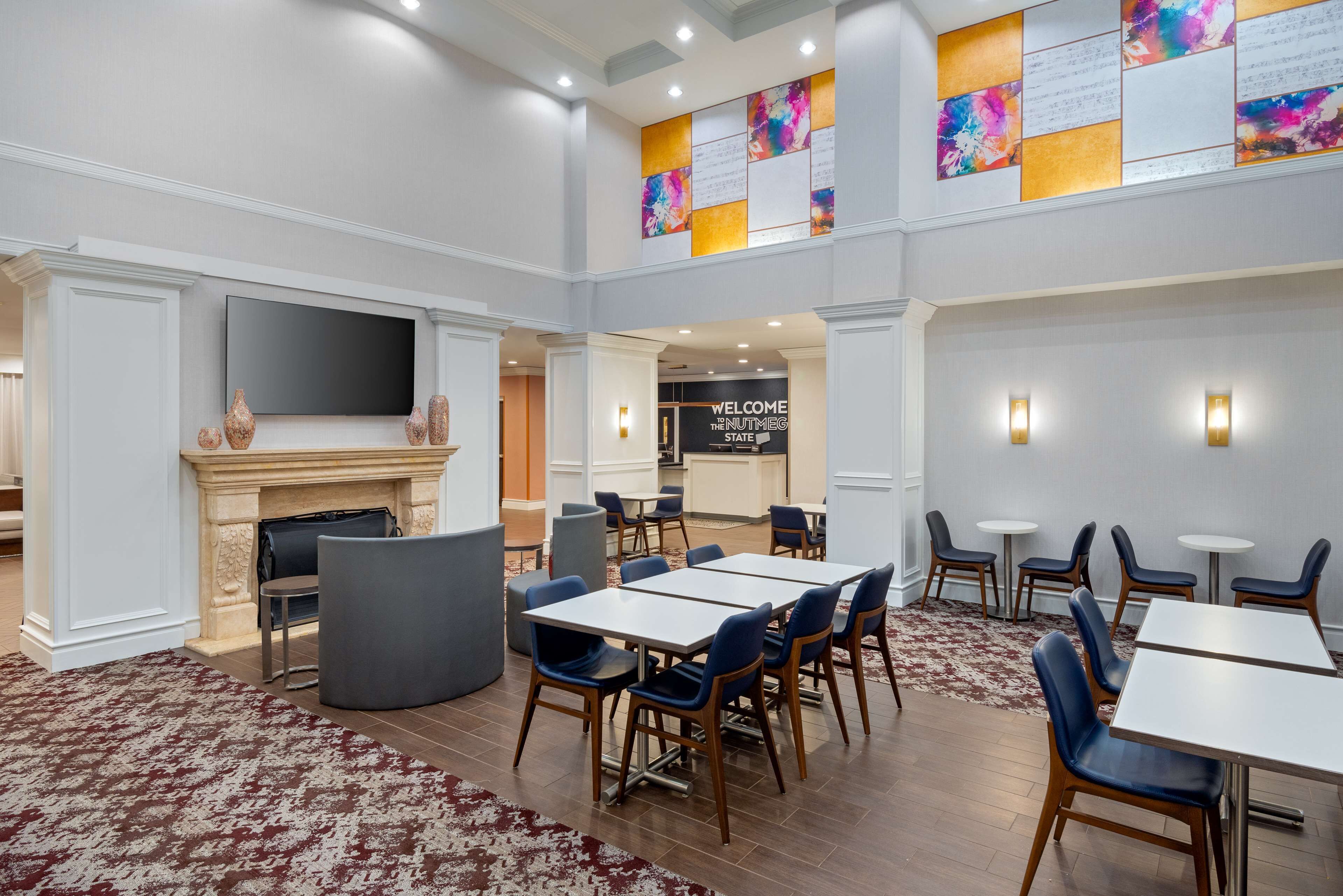A spacious lobby with a fireplace, a large flat-screen TV, and a reception desk.